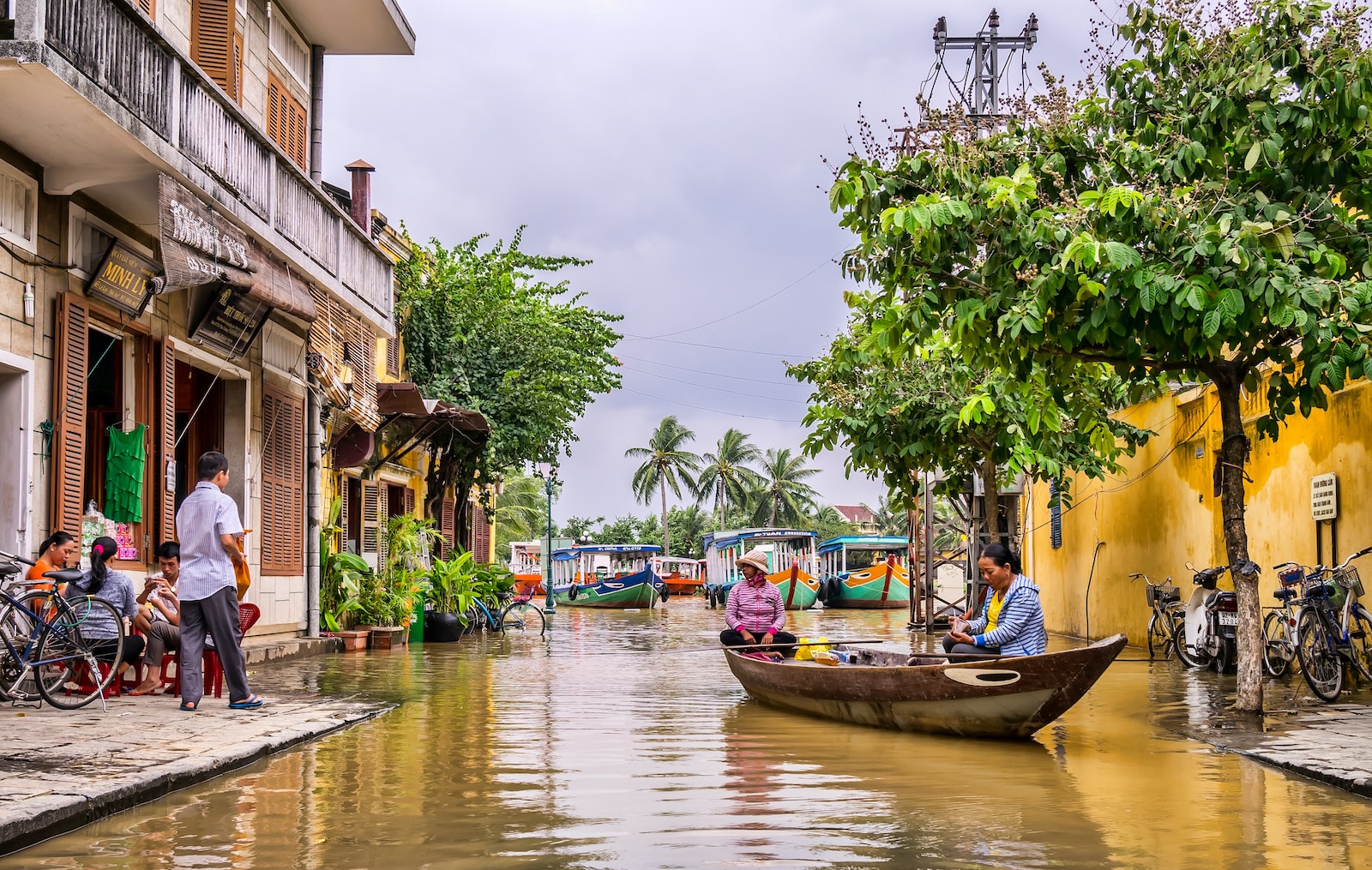 two women riding boat beside brown house