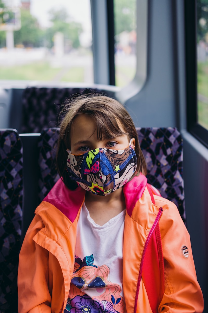 Photo by Miikka Luotio girl in orange jacket wearing blue mask