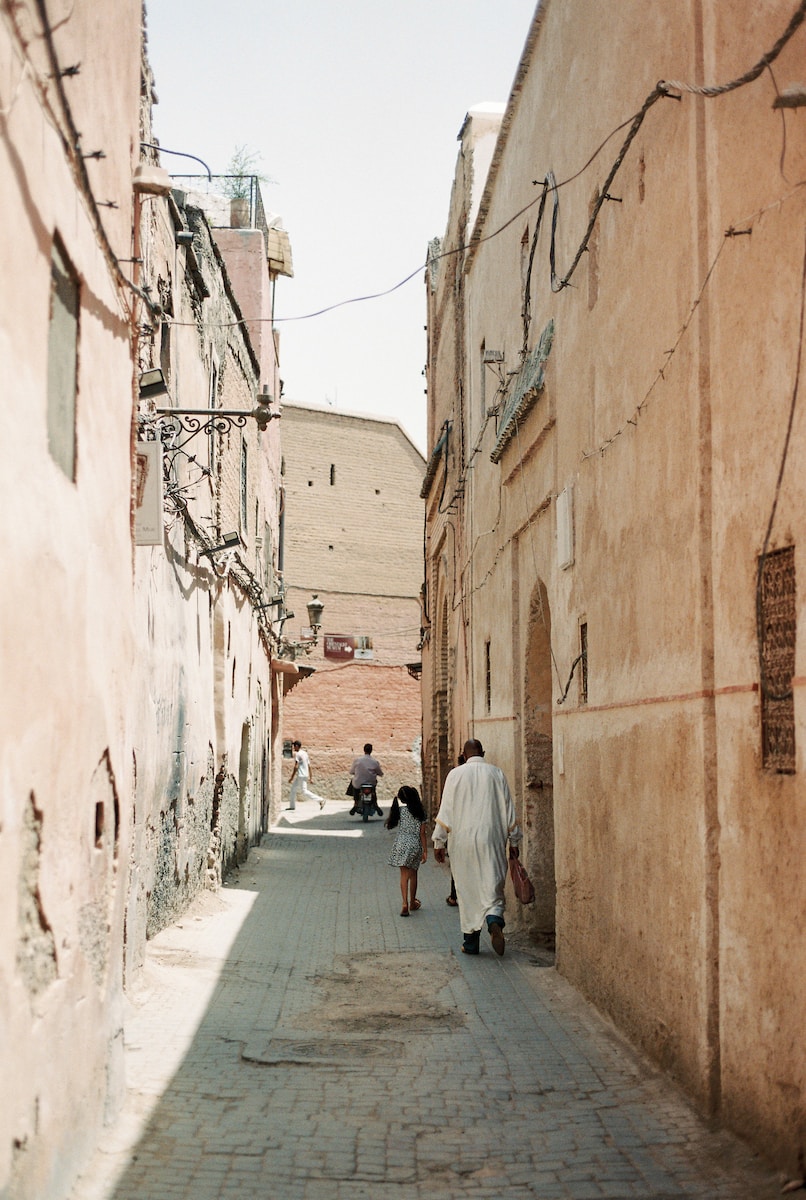 Photo by Nadia Meli man in white thobe walking on sidewalk during daytime